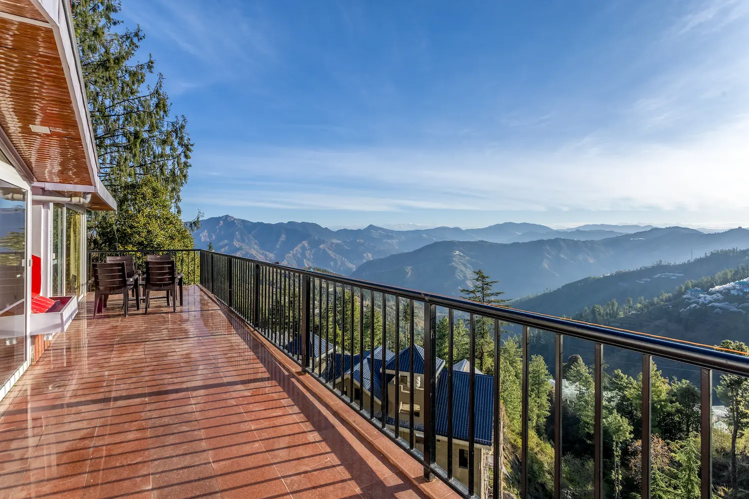 The villa's long terrace balcony with seating, looking out over layered blue mountains