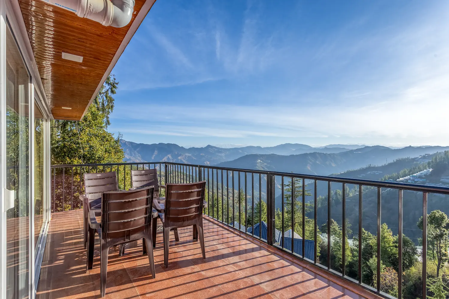 Chairs gathered on the balcony under its timber soffit, with the Himalayas stretching to the horizon