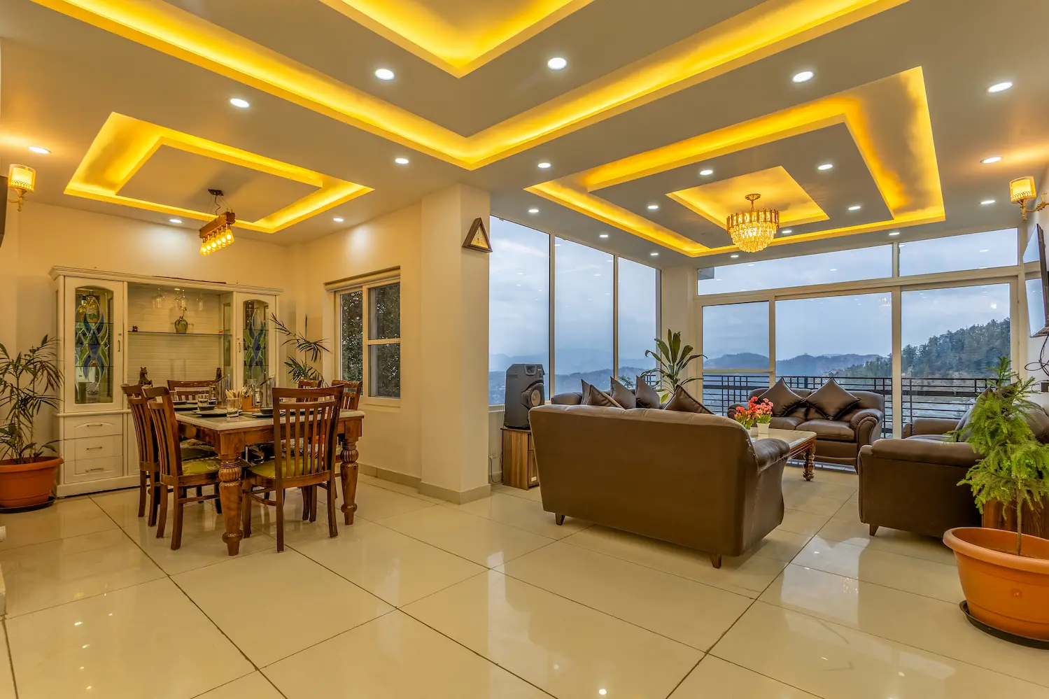 Open-plan main floor: the dining table on one side, leather sofas on the other, glass running the length of the valley