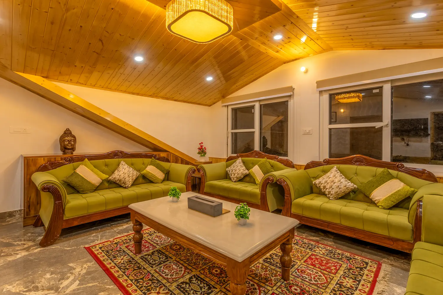 Green sofas and a low table in the villa's upstairs lounge, set for a long evening